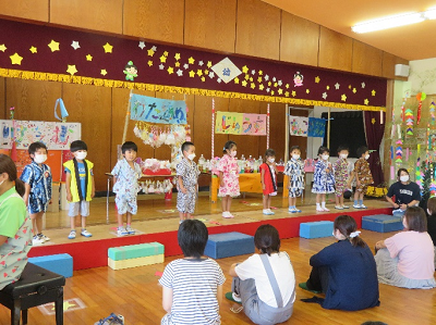 遊戯室で保護者の前で発表をする浴衣姿の園児たちの写真