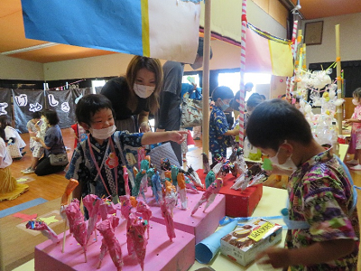手作りの屋台セットで買い物をしている園児と保護者の写真