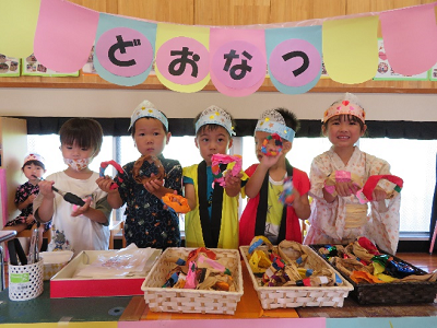 手作りの屋台セットの中で横に並んでポーズをとる園児たちの写真