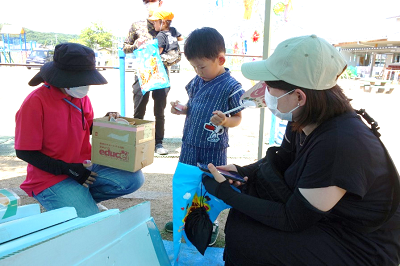 保護者やPTA役員に見守られながらくじ引きを楽しむ園児の写真