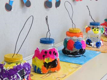 黄色や青の蓋がついたビンに紙粘土が貼り付けられ、カラフルな色で装飾された子どもたちの作品の写真
