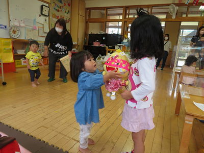 おもちゃの人形を手渡して遊ぶ子どもたちの写真