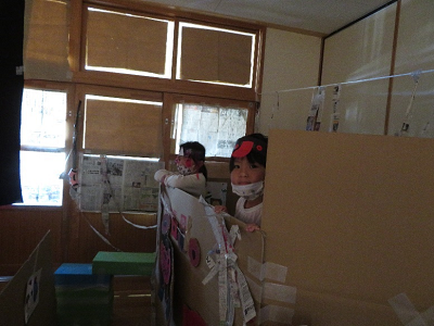 室内の段ボールの船の中で海賊帽をかぶった子供たちが顔をのぞかせている写真