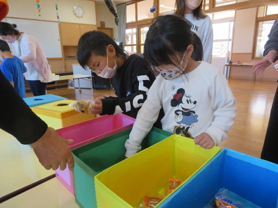 室内のコーナーで子供たちがカラフルな箱の中から景品を選んでいる写真