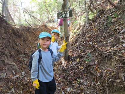 登山道の「5合目」の看板の前で園児たちがピースサインをして立っている写真