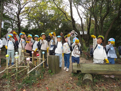 森の中の広場で園児たちが手を伸ばしてヤマガラを待っている写真