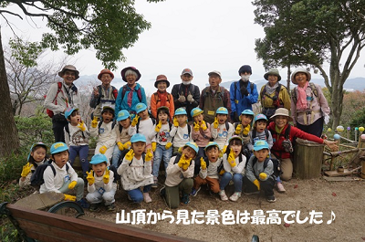「山頂から見た景色は最高でした」と白文字で書かれ、山頂で園児と職員が全員で記念撮影している写真