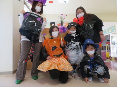 室内でハロウィーンの仮装をした園児と先生が並んでポーズをとっている写真