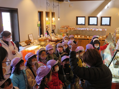 店内で園児が店員の説明を聞いている写真