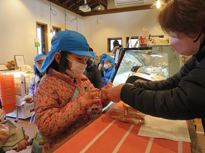 店内で園児が店員に商品を渡して会計している写真