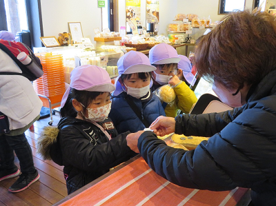 店内で園児が店員に代金を渡している写真