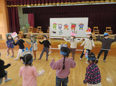 頭にそれぞれ手作りのお面を被った園児たちが身体全体を使って元気に鬼のパンツを踊っている写真