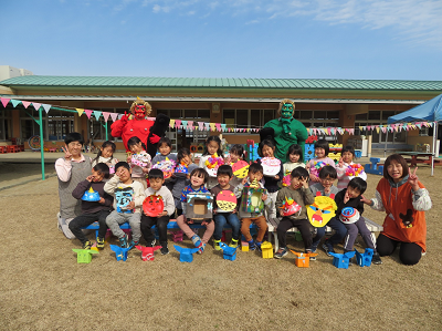 園庭で赤鬼と緑鬼と並んで集合写真を撮る園児たちの写真