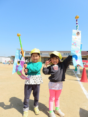 きれいな青空と同じ空色の手作りこいのぼりを片手に持った男の子と女の子の写真