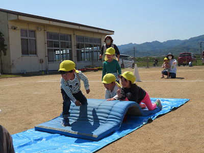 水色のマットで作られた障害物を這って乗り越えている園児たちの写真