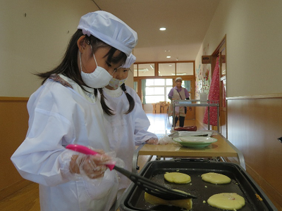 園の廊下でホットプレートを使い真剣な表情でホットケーキを焼いている2人の園児の写真
