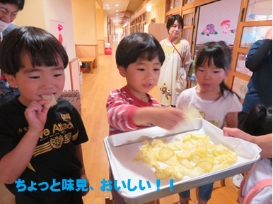 出来上がったばかりのポテトチップスを一枚味見して笑顔を見せている園児たちの写真