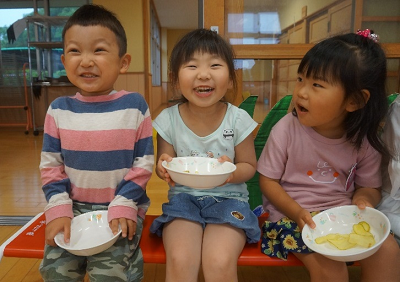 ポテトチップスを食べて笑顔で写真に写っている一人の男の子と2人の女の子の写真