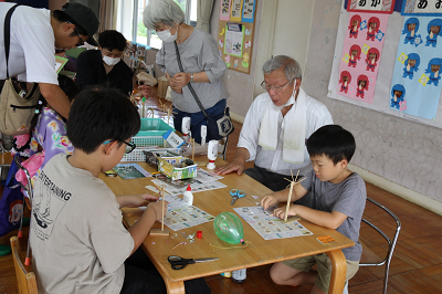 男の子二人が男性に指導を受けながら竹細工を作っている「バンジョイ塾」さんの竹細工コーナーの写真