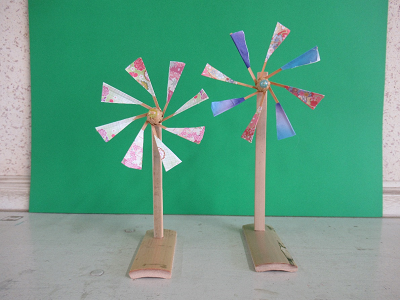 ピンクや白、紫色で装飾された2つの竹細工の風車の写真