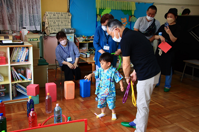 水色の浴衣を着た男の子が男性に付き添われながら輪投げを楽しんでいる写真