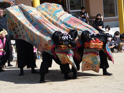 色鮮やかな布をまとった獅子がパフォーマンスしている様子の写真