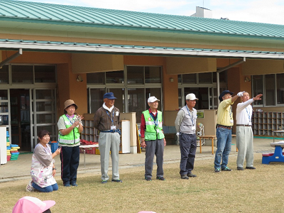 ボランティアの方々が横一列に並び、先生がマイクを持って名前を聞いてる様子の写真