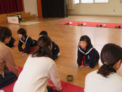 園児たちがそれぞれ保護者と向かい合うように正座で座り、お辞儀をしている様子の写真