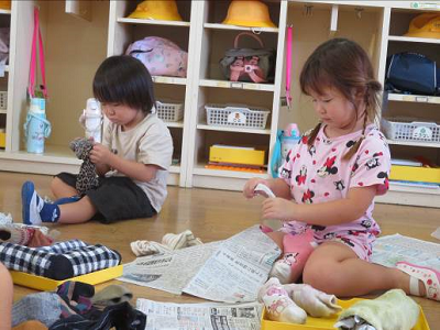 保育室で園児たちが靴下に新聞紙を詰めて作品づくりをしている写真