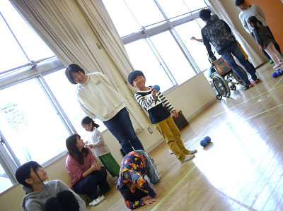 体育館で男の子が青いボールを構えてゲームに参加している写真