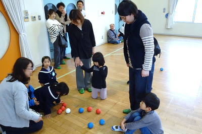 床に集まった赤と青のボールを囲んで親子が結果を確認している写真