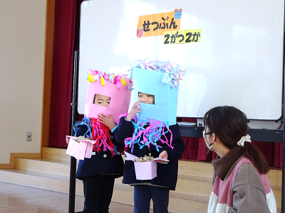 体育館で園児2人が鬼のお面をつけて豆まきをしている写真