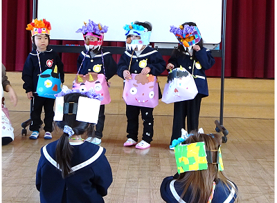 体育館で園児たちが鬼のお面をつけて発表している写真