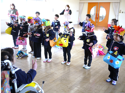 教室で園児たちが鬼のお面をつけて歌に合わせて手を動かしている写真