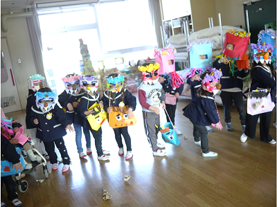 教室で園児たちが鬼のお面をつけて横一列に並んでいる写真