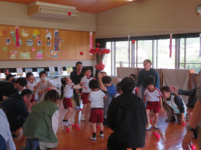 園児と保護者が一緒に赤い玉入れを楽しんでいる写真