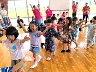 室内のフロアで浴衣姿の子どもたちが列になって踊りを踊っている写真