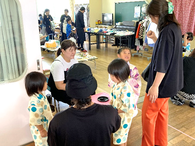 室内の売り場前で浴衣姿の子どもたちが女性二人と話している写真