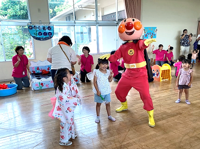 室内のホールでアンパンマンの着ぐるみと浴衣姿の子どもたちが嬉しそうに並んでいる写真