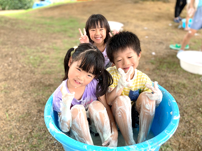 たらいに入って全身泡だらけになりながらピースサインをしている子どもたちの写真