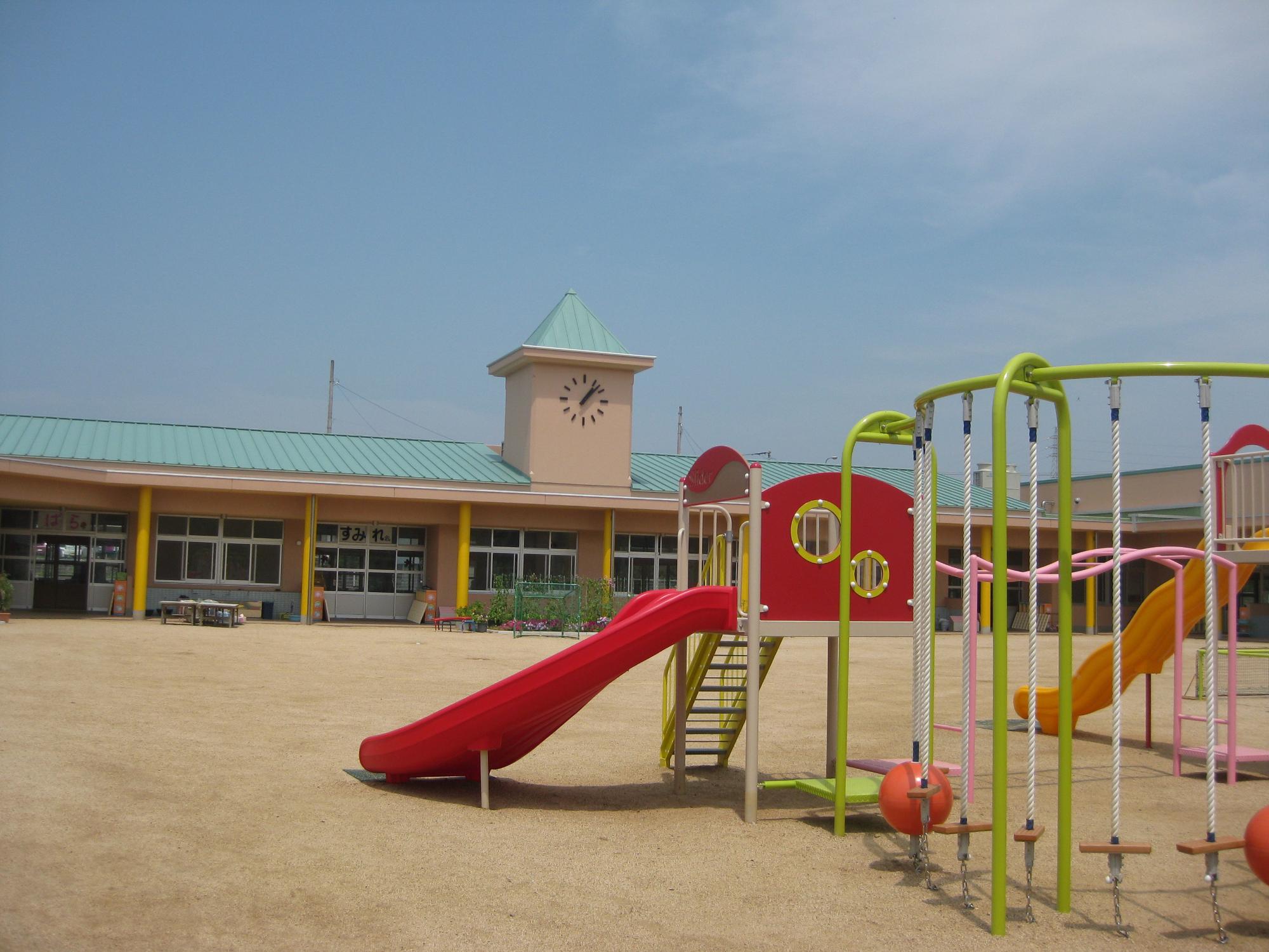 黄緑色の屋根と、グラウンドの赤い滑り台が特徴的なさぬき南幼稚園の写真