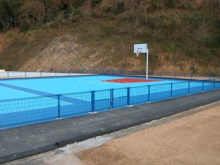 遠くに法面が見えて青色を基調とした床とバスケットコートの写真