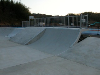 遠くに樹木が見えて灰色を基調とした斜面があるスケート場の写真