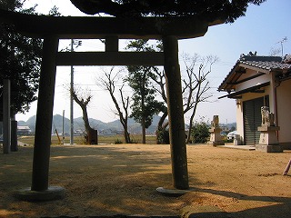 木々に囲まれた敷地にある、中央に塩釜神社の鳥居と切妻屋根の拝殿が右側に写っている写真