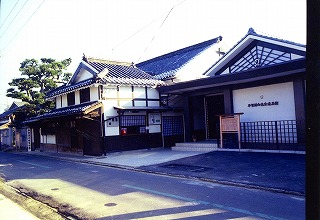 路面の奥に建てられた瓦屋根の古い大きな屋敷の写真