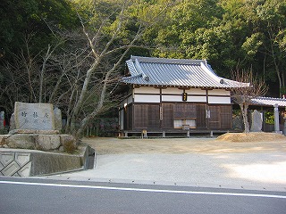 建物名称石看板の奥のやや小高い所に建てられた小ぢんまりとした瓦屋根の屋敷の写真