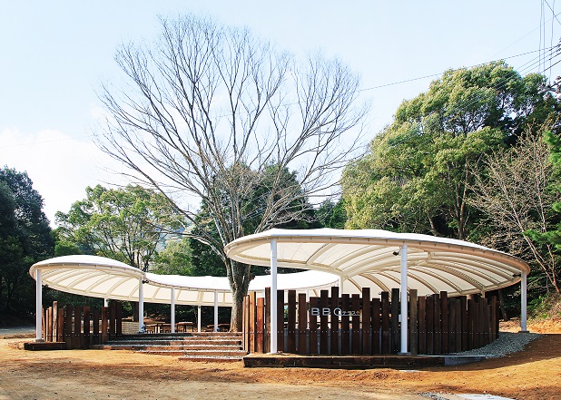 枯れ木を囲むようにして建つ白い屋根の建物の写真
