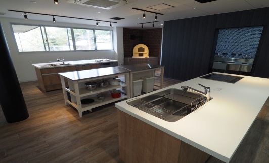 ピザ窯と二つのキッチン台と作業台がある部屋の写真