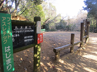 看板の横に丸太を組み合わせて作られたアスレチックが設置されている写真