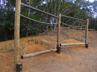 三本の木の柱をロープや丸太が繋ぐように組まれたアスレチックの写真